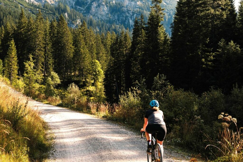 una ragazza che va in bici su un sentiero sterrato tra i boschi