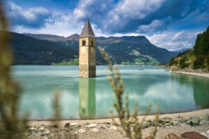 foto del lago di Resia con il campanile della torre di Curon che esce dall'acqua